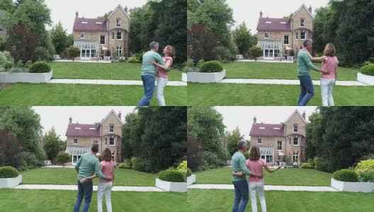 一对快乐的夫妇在花园里拥抱，看着他们的大房子高清在线视频素材下载