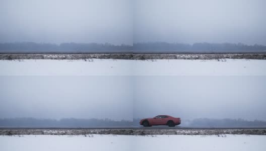 红色的肌肉车行驶在被白雪覆盖的田野包围的高速公路上高清在线视频素材下载
