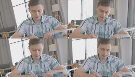 一个年轻人在咖啡馆里用圆珠笔写字，慢镜头高清在线视频素材下载