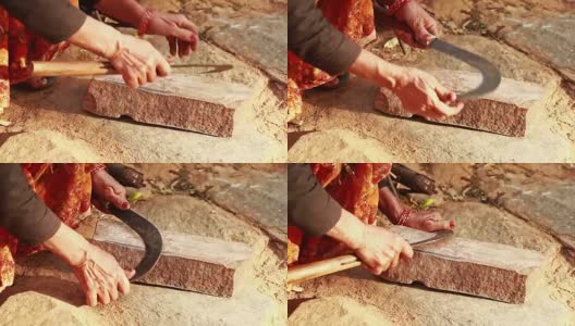 印度农村妇女在磨镰刀(木工工具)的刀刃高清在线视频素材下载