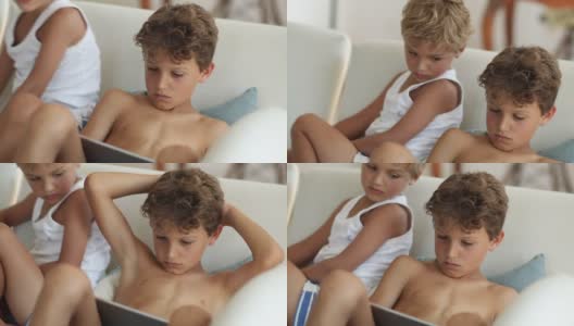 男孩们坐在沙发上用平板电脑看娱乐媒体高清在线视频素材下载