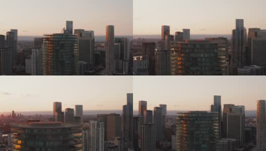 巴尔的摩塔顶部的幻灯片和平移镜头。圆柱形公寓建筑，周围有露台。金丝雀码头区的摩天大楼和日落时的城市景观。英国伦敦高清在线视频素材下载