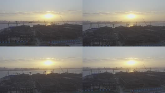 一个大型建筑工地在日落前的背光航拍视频，一个巨大的太阳在天空中高清在线视频素材下载