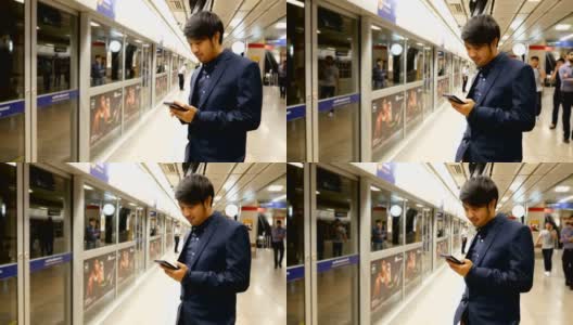亚洲商人在火车站等车时用智能手机发短信高清在线视频素材下载
