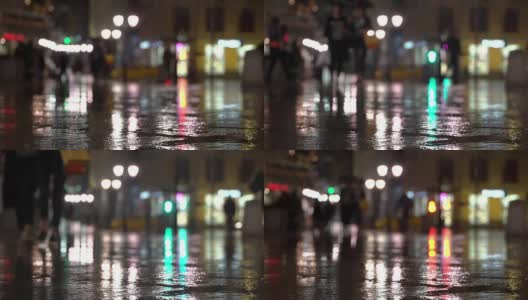 抽象明亮模糊的背景与雨滴，沥青照明路灯和交通灯。身份不明的女孩在雨夜的城市街道上。商店橱窗和街灯在潮湿的路面上发出明亮的照明和反射高清在线视频素材下载