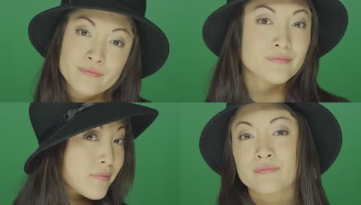 美丽的年轻亚洲女人戴着一顶帽子，看起来严肃，在一个绿色屏幕的工作室背景高清在线视频素材下载