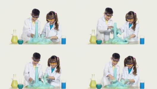 两个可爱的化学家孩子做有趣和成功的实验与蓝色泡沫，玩，孤立在白色的背景高清在线视频素材下载