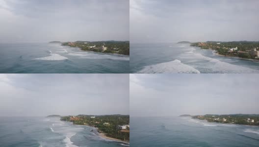 无人机在空中拍摄的田园诗般的泡沫海浪到达壮观的热带度假村海岸的建筑高清在线视频素材下载