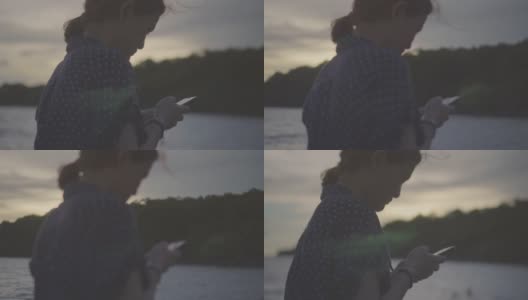 一个年轻女子在海边用智能手机的特写，慢镜头高清在线视频素材下载