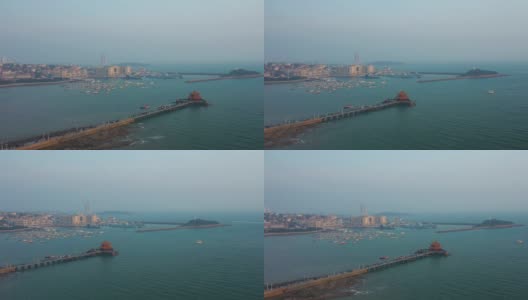 阳光明媚的夜晚青岛著名的海滩湾码头宝塔拥挤的码头航拍全景4k中国高清在线视频素材下载