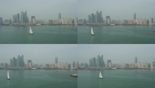 白天青岛市区海岸线海湾纪念碑帆船航行航拍全景4k中国高清在线视频素材下载