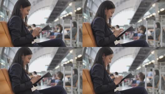 商务女性在候机大厅候机时使用平板电脑高清在线视频素材下载