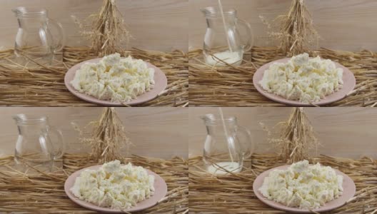 牛奶装在玻璃杯里。以稻草和木板为背景的白干酪盘高清在线视频素材下载
