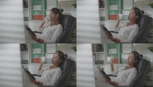 亚洲妇女她在家里工作她在工作的时候喝咖啡。高清在线视频素材下载