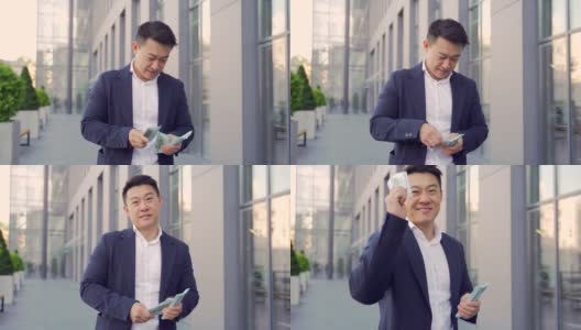 一位成功的亚洲商人一边数着钱，一边伸出手看着相机高清在线视频素材下载