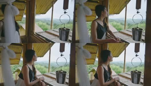 亚洲妇女在木屋度假胜地的窗边看自然风景高清在线视频素材下载