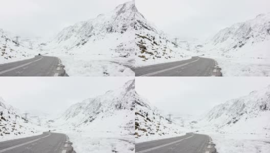 一辆黑色轿车在雪山之间的发夹弯道上行驶高清在线视频素材下载