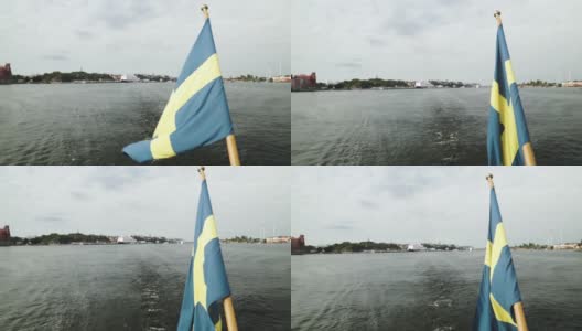 瑞典国旗在风中飘扬的船尾馈水旗杆在斯德哥尔摩城市中心港口航行高清在线视频素材下载
