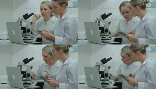 穿着实验服的研究人员在明亮的实验室里用显微镜检查样品，使用数码平板电脑，在笔记本电脑上做笔记高清在线视频素材下载