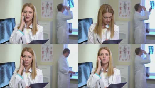 年轻的女医生与一个病人在电话和男医生看x光的背景。高清在线视频素材下载