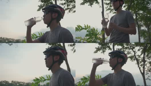 亚洲年轻活跃的男性经常喝瓶装水，骑完自行车后要休息。运动员在城市公园通过自行车运动锻炼身体，增进身体健康。高清在线视频素材下载