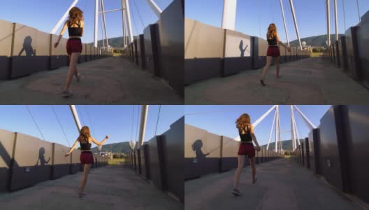 女孩在一座现代化的人行桥上行走、旋转和跳舞高清在线视频素材下载