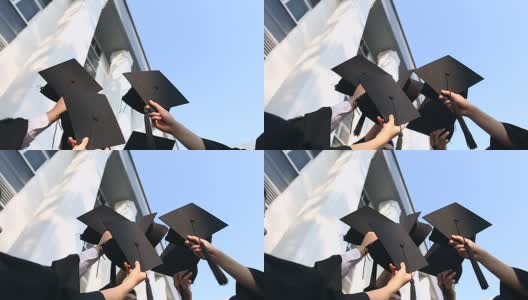 快乐的学生们穿着长袍，把学位帽抛向空中。教育、毕业与人理念-高清在线视频素材下载
