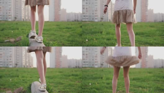 小女孩的腿走在水泥原木上，跳在城市草坪上的草地上高清在线视频素材下载