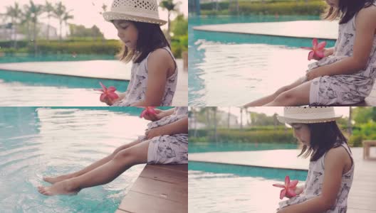 一个小女孩坐在池边，脚浸在水里，高清在线视频素材下载