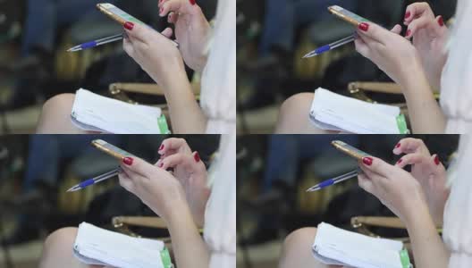 一个女性手握一支笔，坐在智能手机上打字短信的特写高清在线视频素材下载