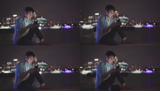 年轻的亚洲男人在晚上用手机高清在线视频素材下载