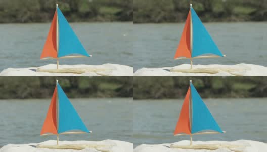 沙滩上是自制的玩具帆船，背景是现在的山河高清在线视频素材下载