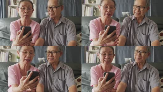 亚洲老年妇女和老人手持手机或平板电脑，在家里与儿子、女儿、孙子、孙女进行视频通话和微笑。祖父母对通过互联网交流感到高兴。高清在线视频素材下载