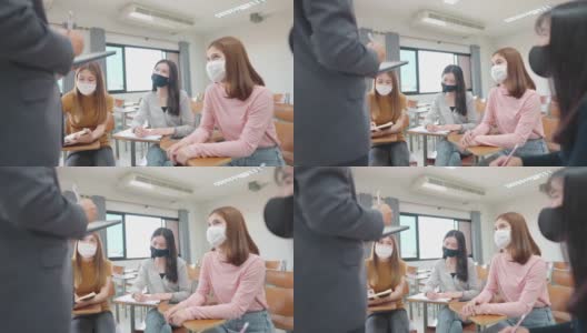 在大学教室里，一位老师用平板电脑给学生上课。学生戴口罩预防病毒新常态。高清在线视频素材下载