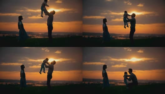 一家人站在夕阳的背景下，父亲将儿子抛向空中，这是一个夏日的傍晚高清在线视频素材下载
