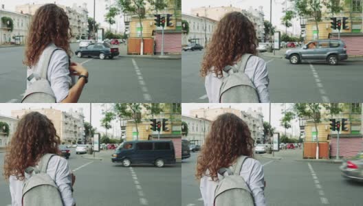 一头卷发背着双肩包的苗条女子在人行横道等待绿灯高清在线视频素材下载