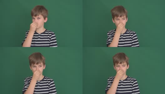 一个小男孩用手指捏着他的鼻子在绿色的屏幕上高清在线视频素材下载
