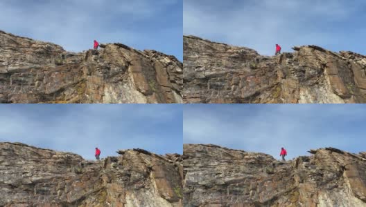 一个穿着红色夹克的人走在岩石山的边缘。高清在线视频素材下载