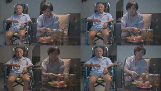 亚洲华人老夫妇坐在轮椅上享受电影之夜，坐在客厅的沙发上看电视高清在线视频素材下载