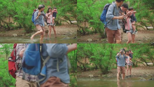领导人的正面观点，亚洲爷爷带领跨越危险的河流，一个父亲和女儿骑在脖子上，母亲跟随勇气男人的脚步与感觉兴奋。冒险和探索多代家庭徒步在热带森林。高清在线视频素材下载