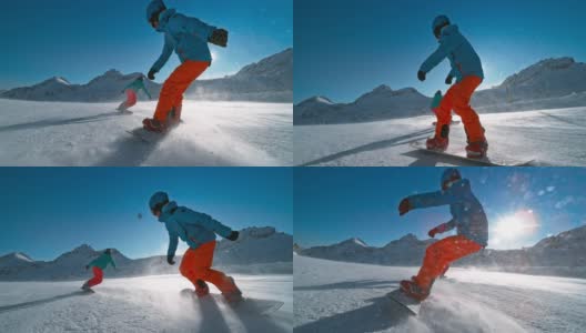 SLO MO TS滑雪板在一个阳光明媚的日子里，在一个朋友后面滑下雪道高清在线视频素材下载