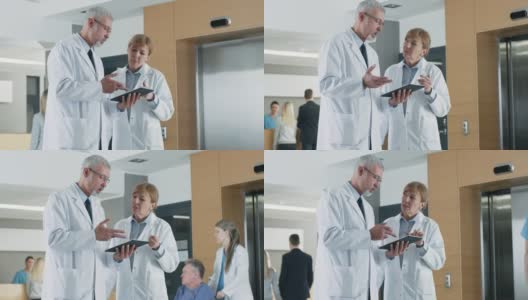 在医院，医生在使用平板电脑时进行讨论。背景:患者与医务人员。新型现代化、功能齐全的医疗设施。高清在线视频素材下载