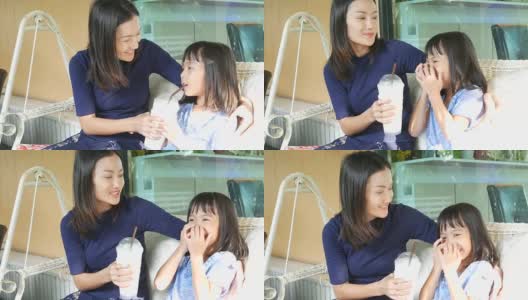 女孩和妈妈在秋千上喝奶昔高清在线视频素材下载