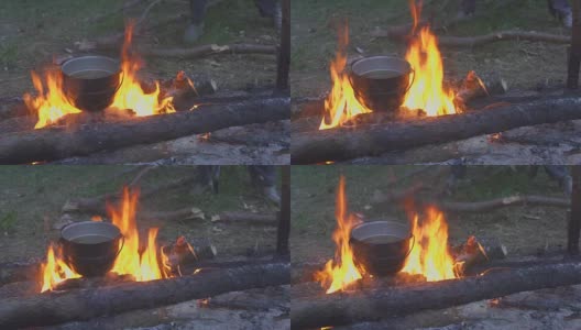 在黄昏森林的篝火上用大锅做饭高清在线视频素材下载