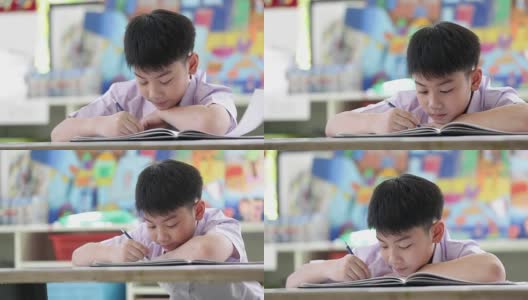 亚裔孩子穿着学生校服做读书写字的学校作业。高清在线视频素材下载