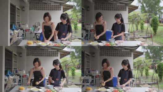 亚裔华人母亲和女儿在后院厨房准备食物。女儿在向母亲学习高清在线视频素材下载