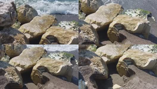 海滩上海浪的运动，击碎了一些岩石，溅起了泡沫。高清在线视频素材下载
