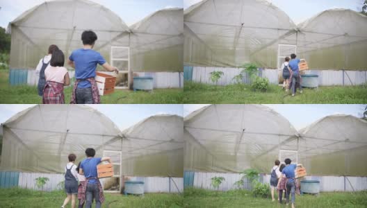 亚裔华裔单亲妈妈带着孩子们，拿着板条箱和篮子走向她的温室高清在线视频素材下载