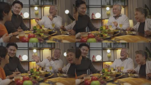 快乐的亚洲家庭围坐在餐桌前享受晚餐。高清在线视频素材下载