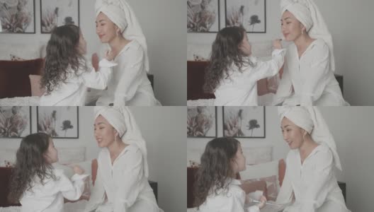 混合亚洲年轻女孩假装扮演化妆师，美容沙龙与她的母亲在床上，家庭生活方式健康的概念高清在线视频素材下载
